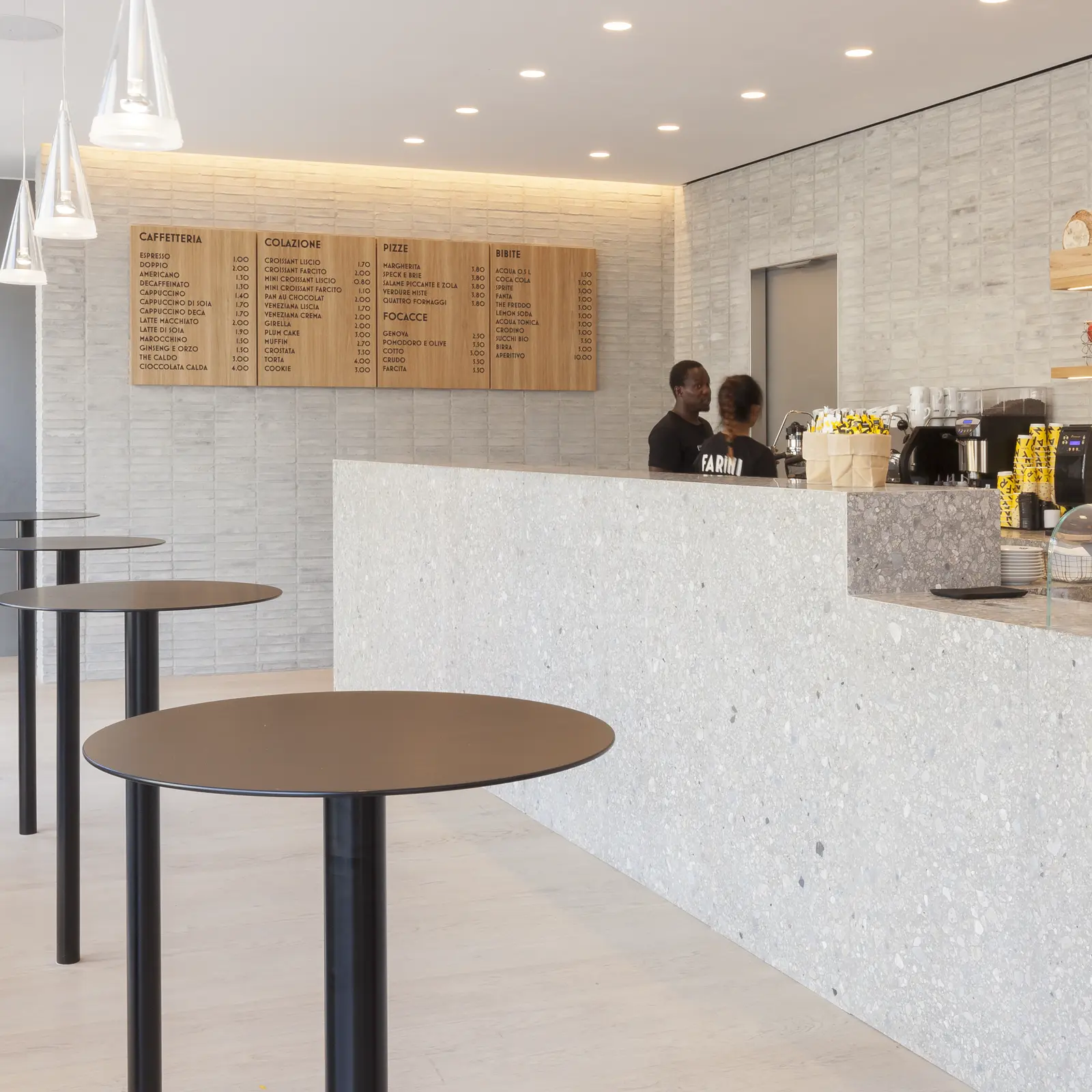 Interno della caffetteria Farini con bancone in pietra, tavolini alti e menu in legno a parete